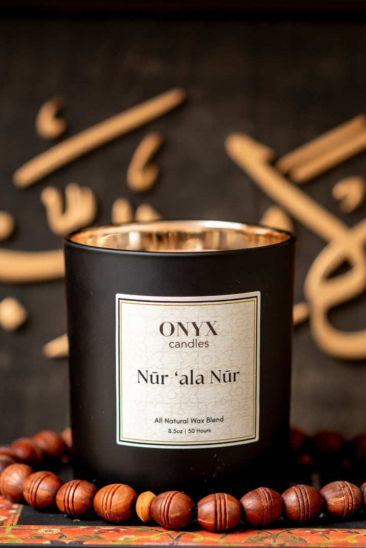 Nūr ‘ala Nūr candle lit with calligraphy backdrop