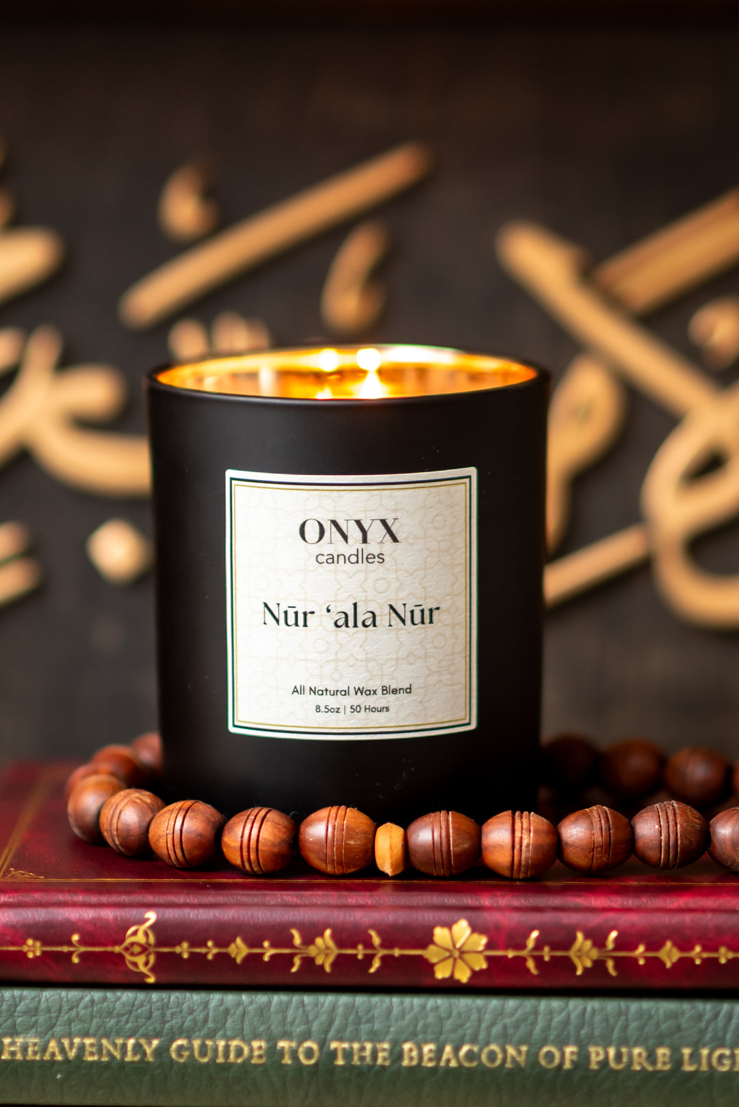 Nūr ‘ala Nūr candle on books with prayer beads